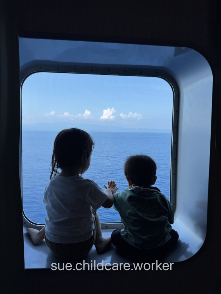 フェリー客室の窓から海を見る子ども